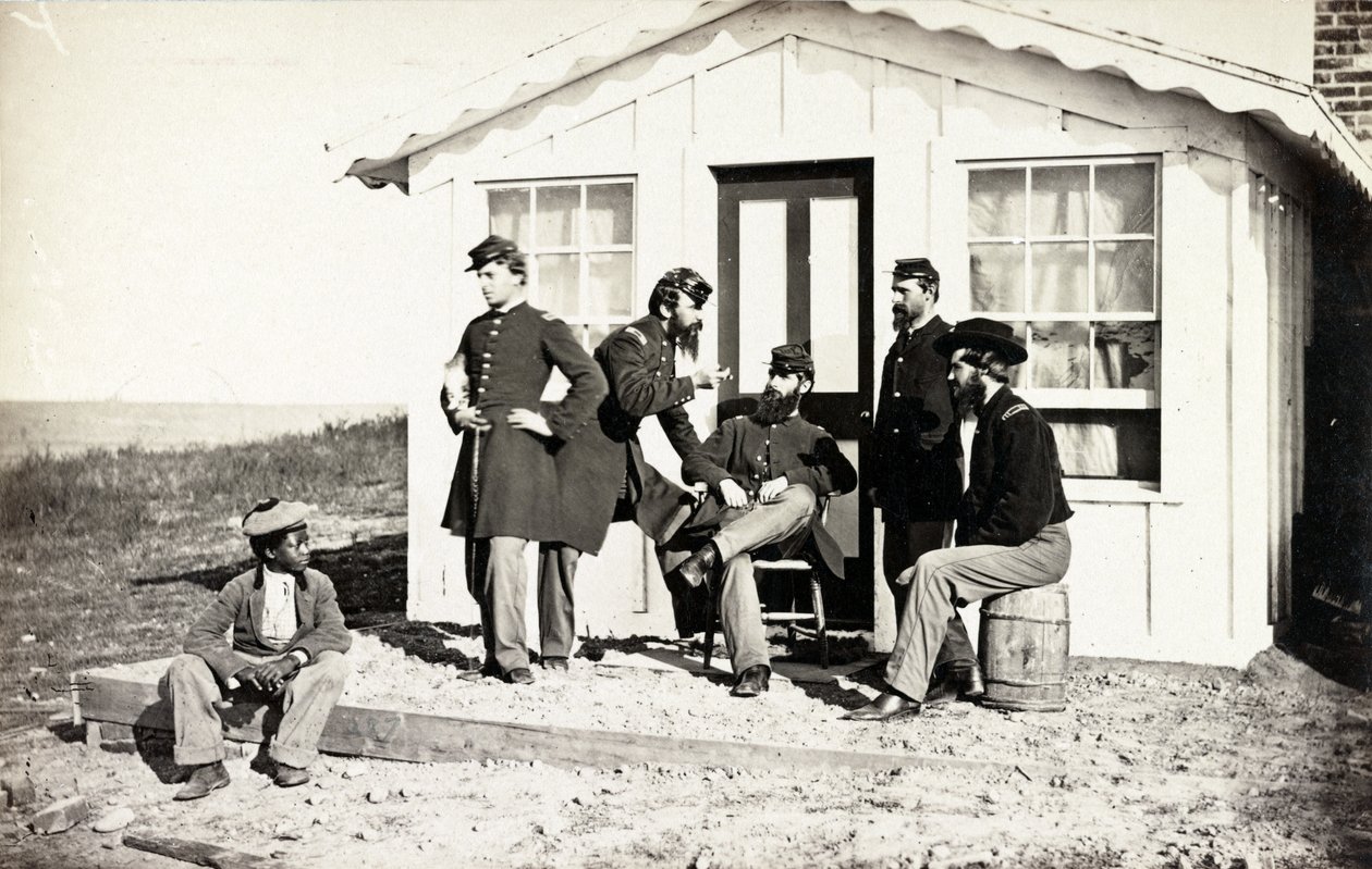 Cinque soldati della Guerra Civile riuniti su un portico di terra fuori casa, giovane afroamericano seduto vicino a loro, 1861-65 da American Photographer