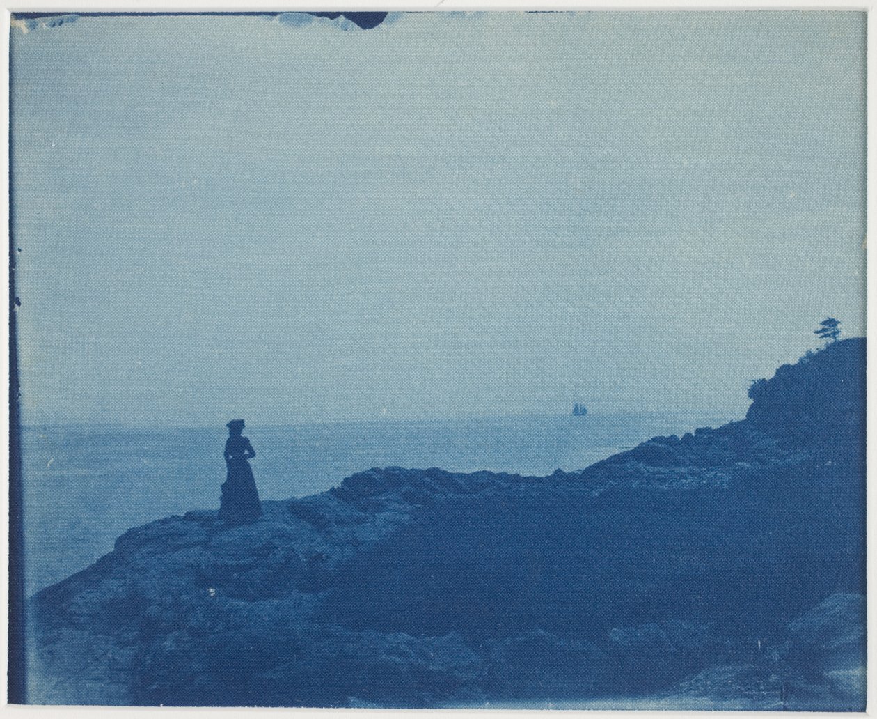 Donna che guarda una goletta da un promontorio roccioso da American Photographer