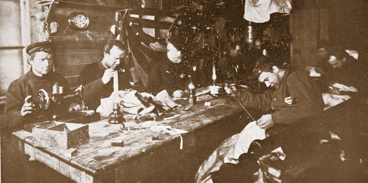 Nella capanna durante il pieno inverno, gli uomini impegnati a cucire pellicce per abiti da usare nelle slitte primaverili, pub. Londra 1907 (foto b/n) da Anthony Fiala