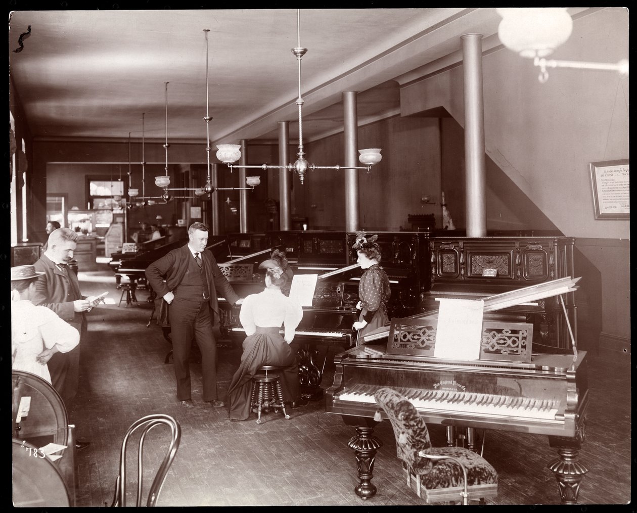 Una sala espositiva della New England Piano Co., 1895 da Byron Company