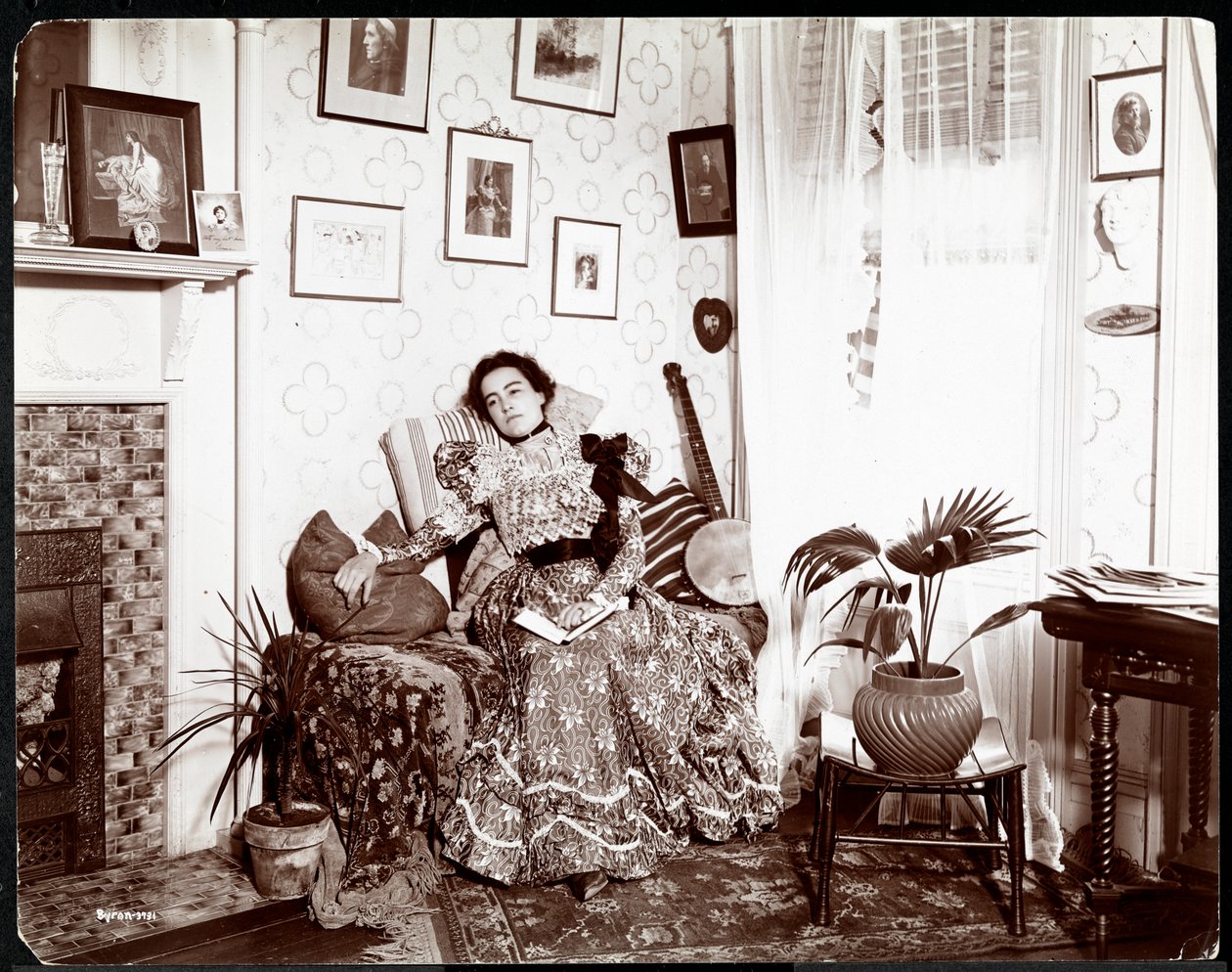 Una donna che si rilassa su una sedia, leggendo un libro, 1896-98 da Byron Company