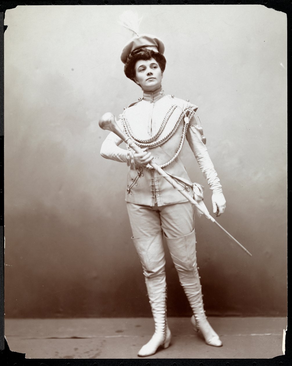 Una donna che modella una divisa da banda, tenendo un bastone, c.1898 da Byron Company
