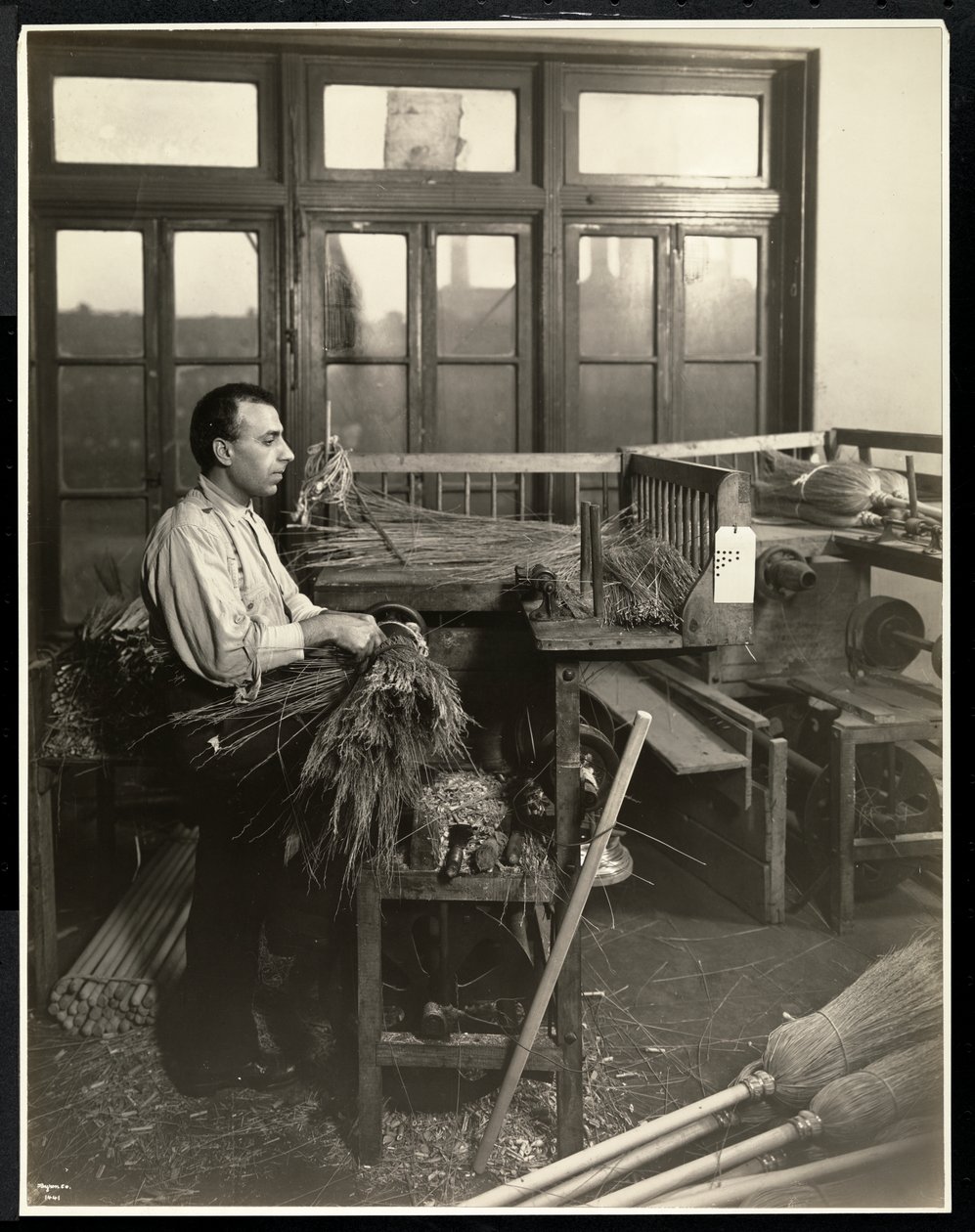 Uomo cieco che fissa la paglia sui manici delle scope al Bourne Memorial Building, New York, 1921 da Byron Company