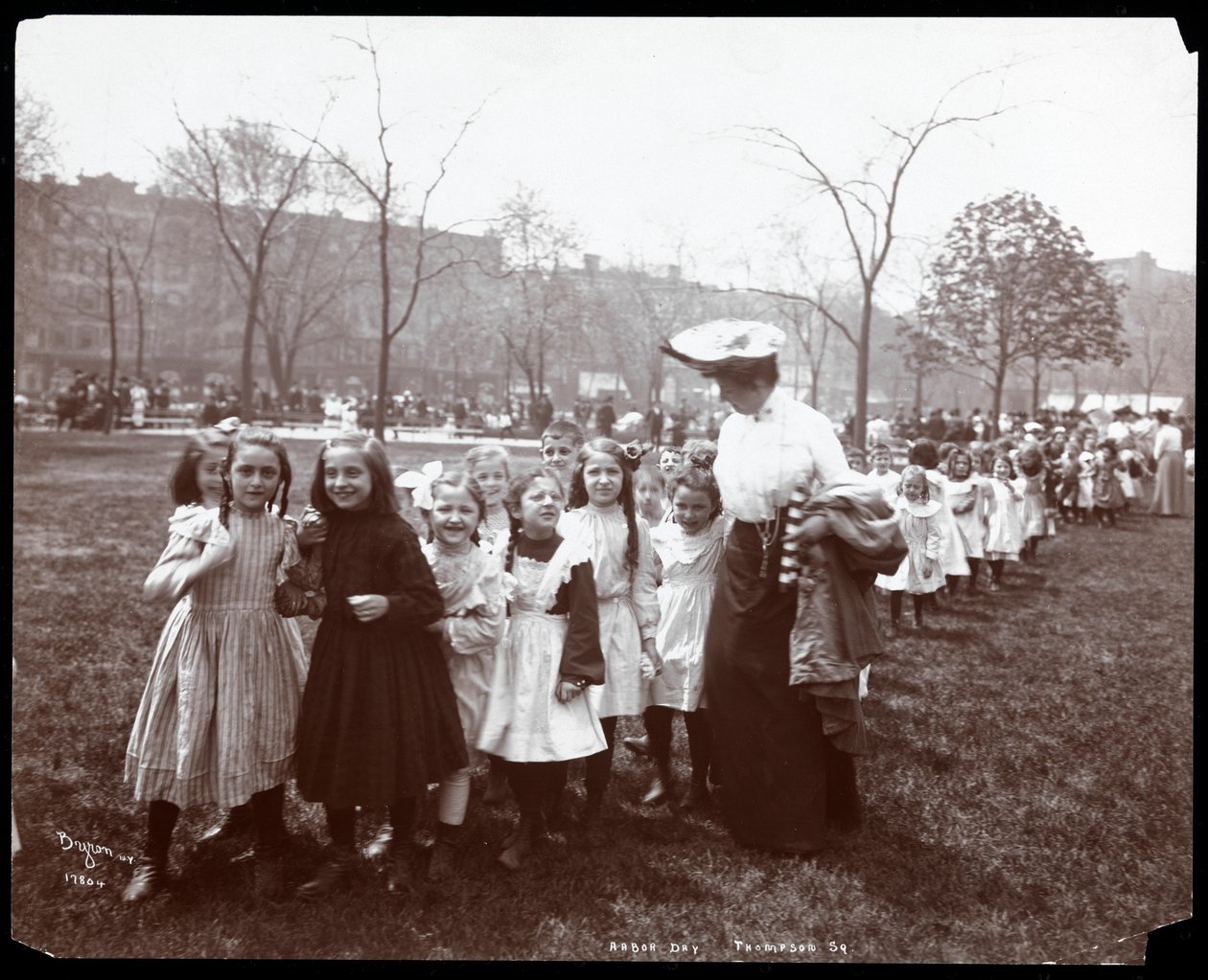 Bambini in una lunga fila guidati da una donna nel Tompkins Square Park, New York, 1904 da Byron Company