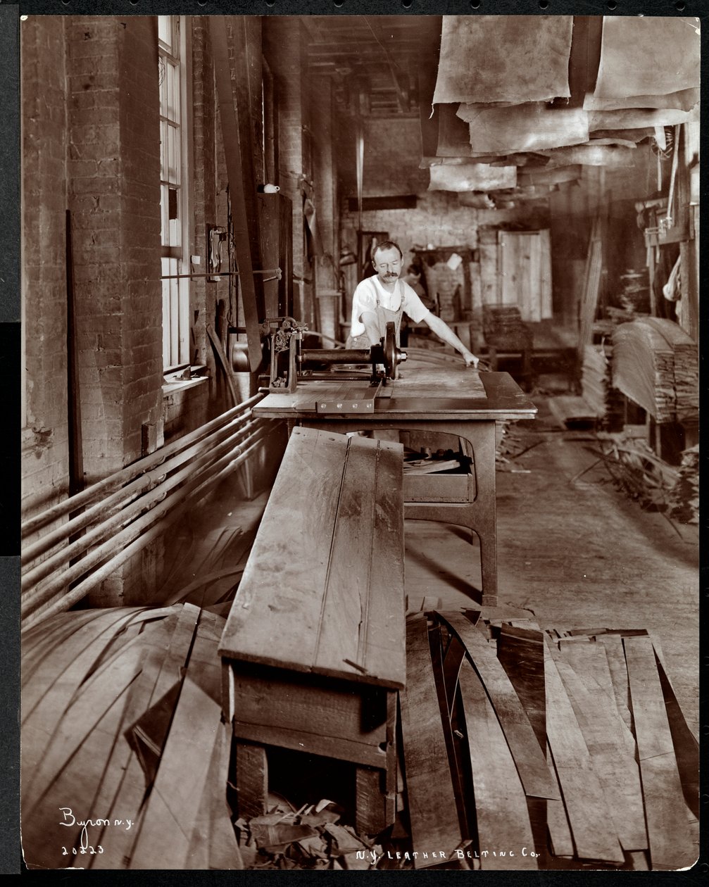 Vista interna di un uomo che lavora con la pelle alla New York Leather Belting Co., New York, 1905 da Byron Company