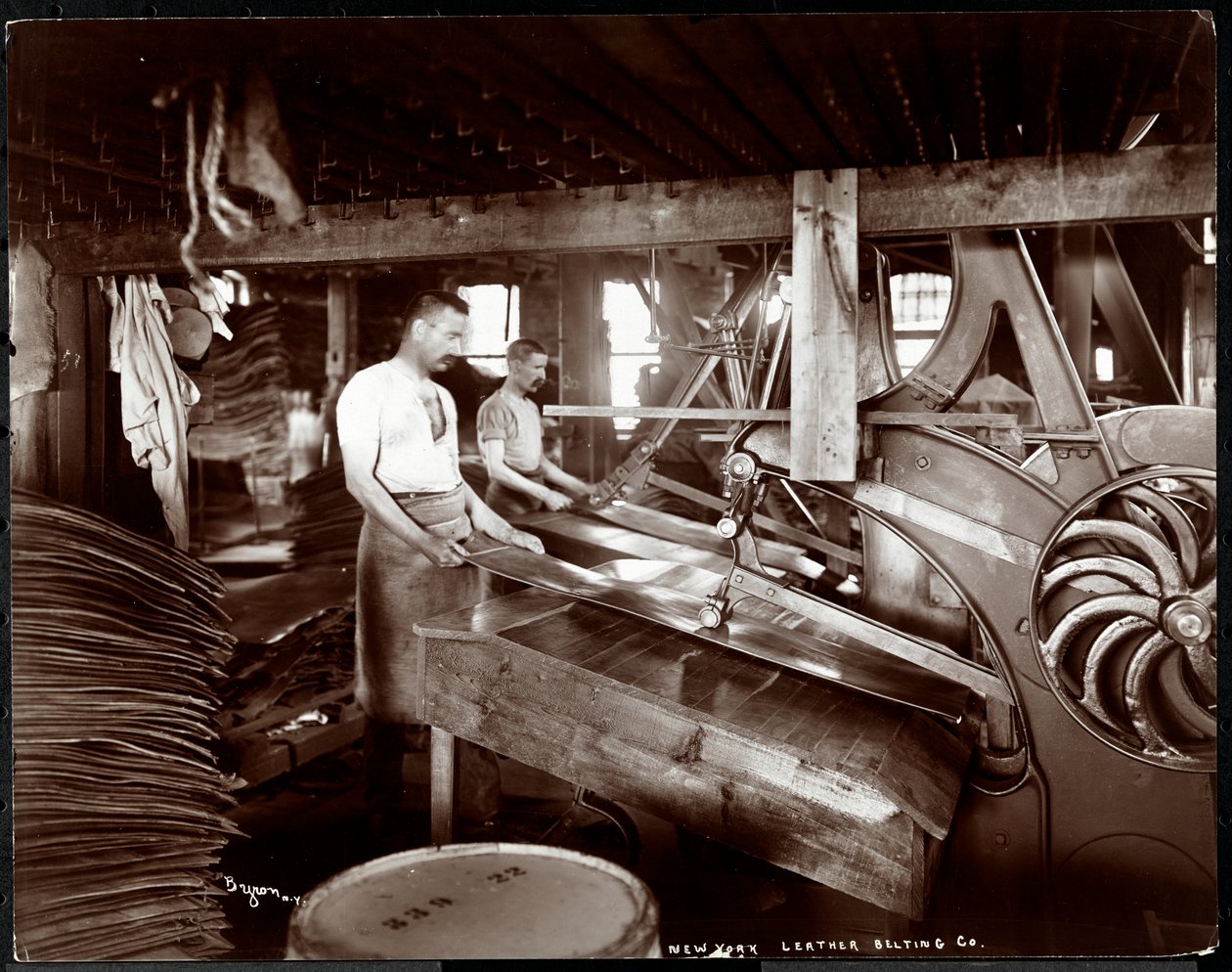 Vista interna di due uomini che lavorano con il cuoio e attrezzature pesanti alla New York Leather Belting Co., New York, 1905 da Byron Company