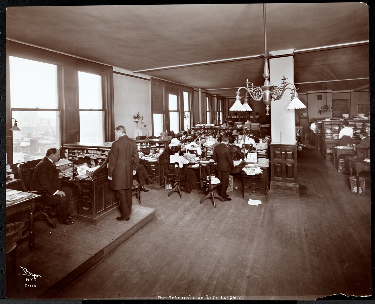 Uomini e donne che lavorano a scrivanie in un ufficio della Metropolitan Life Insurance Co. a 23rd Street e Madison Avenue, New York, 1907 da Byron Company