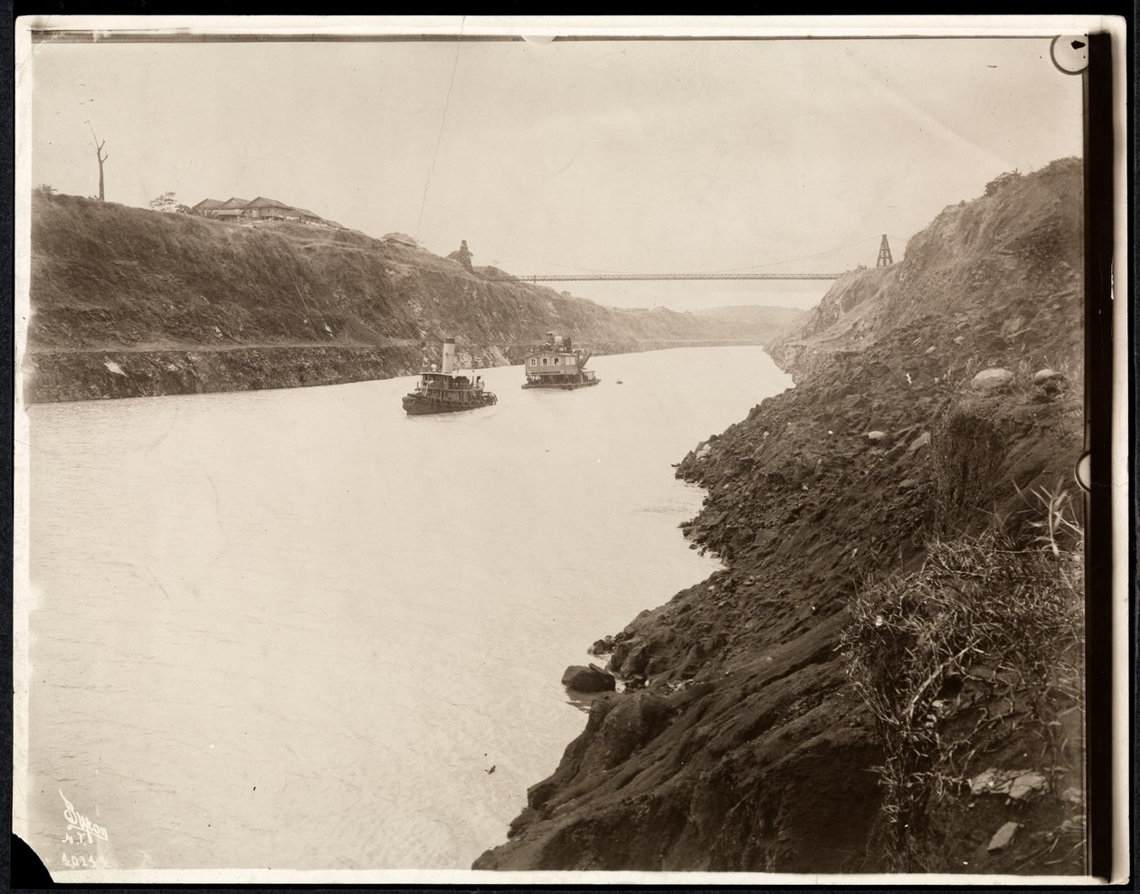 Veduta di due barche nel Canale di Panama durante la sua costruzione con un ponte sospeso oltre, 1913 da Byron Company