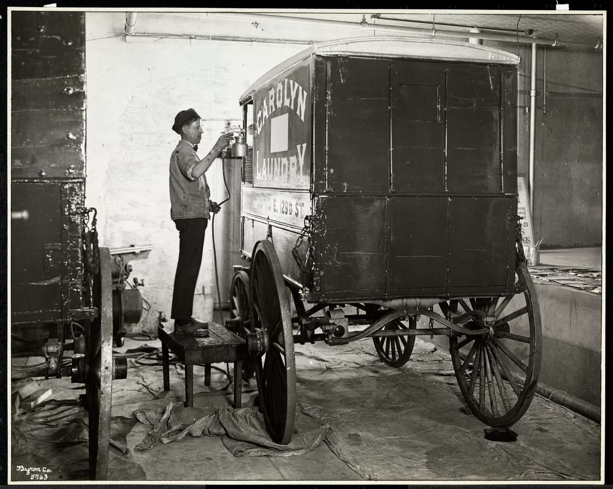Un uomo che spruzza vernice su un carro di consegna della Carolyn Laundry a 111 East 128th Street, East Harlem, New York, 1929 da Byron Company