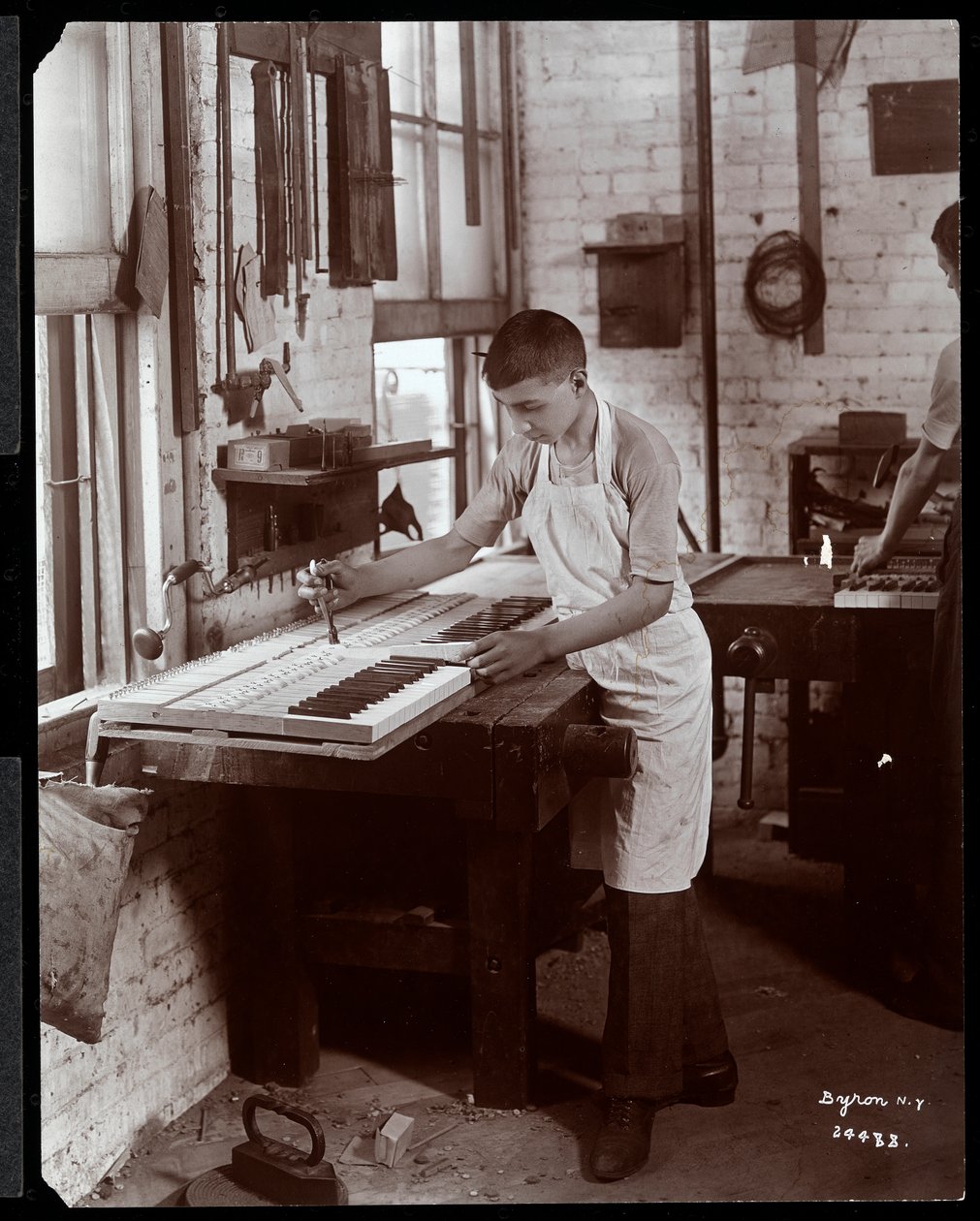Un giovane che lavora nella fabbrica di pianoforti Harrington, 1907 da Byron Company