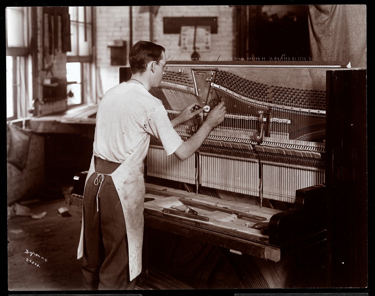 Uomo che lavora nella fabbrica di pianoforti Hardman, Peck e Co., New York, 1907 da Byron Company