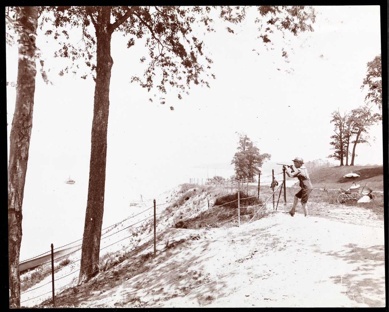 Vista di un ragazzo con un cannocchiale che guarda verso il fiume Hudson dal Riverside Park, New York da Byron Company