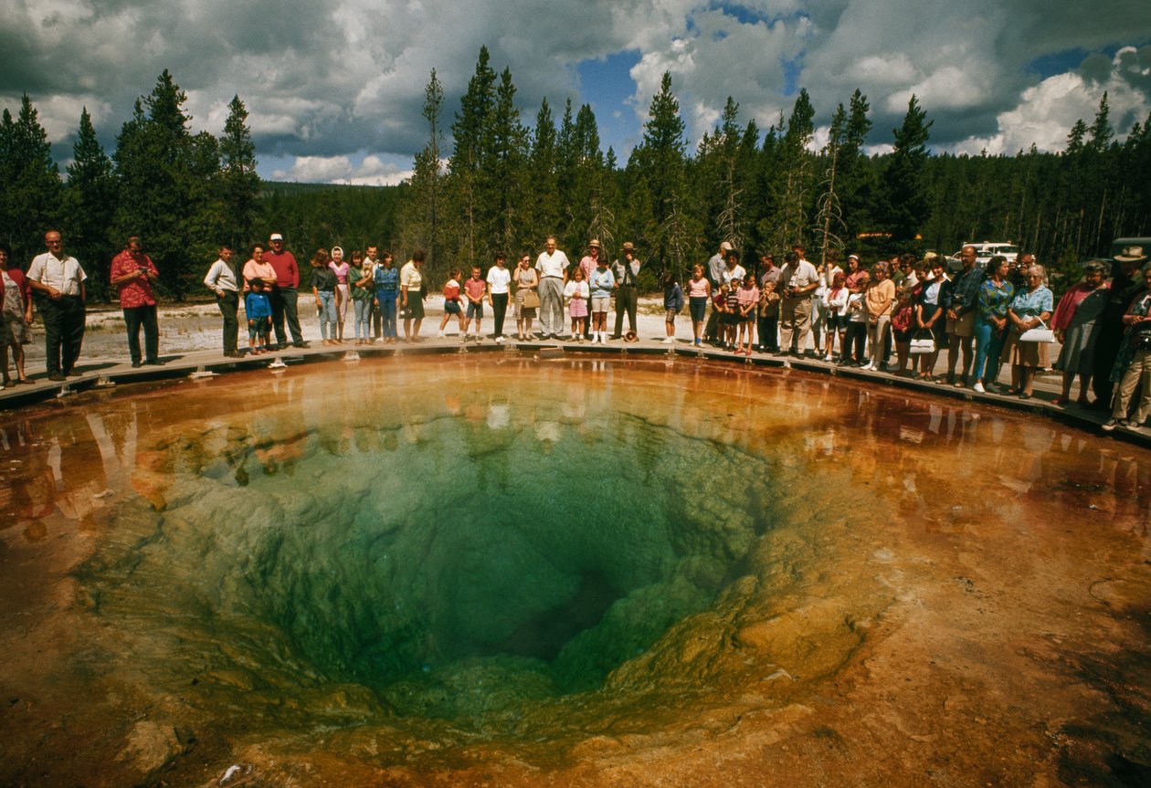 I visitatori del parco si radunano attorno a una piscina termale a forma di fiore blu-verde. Parco Nazionale di Yellowstone da Dean Conger