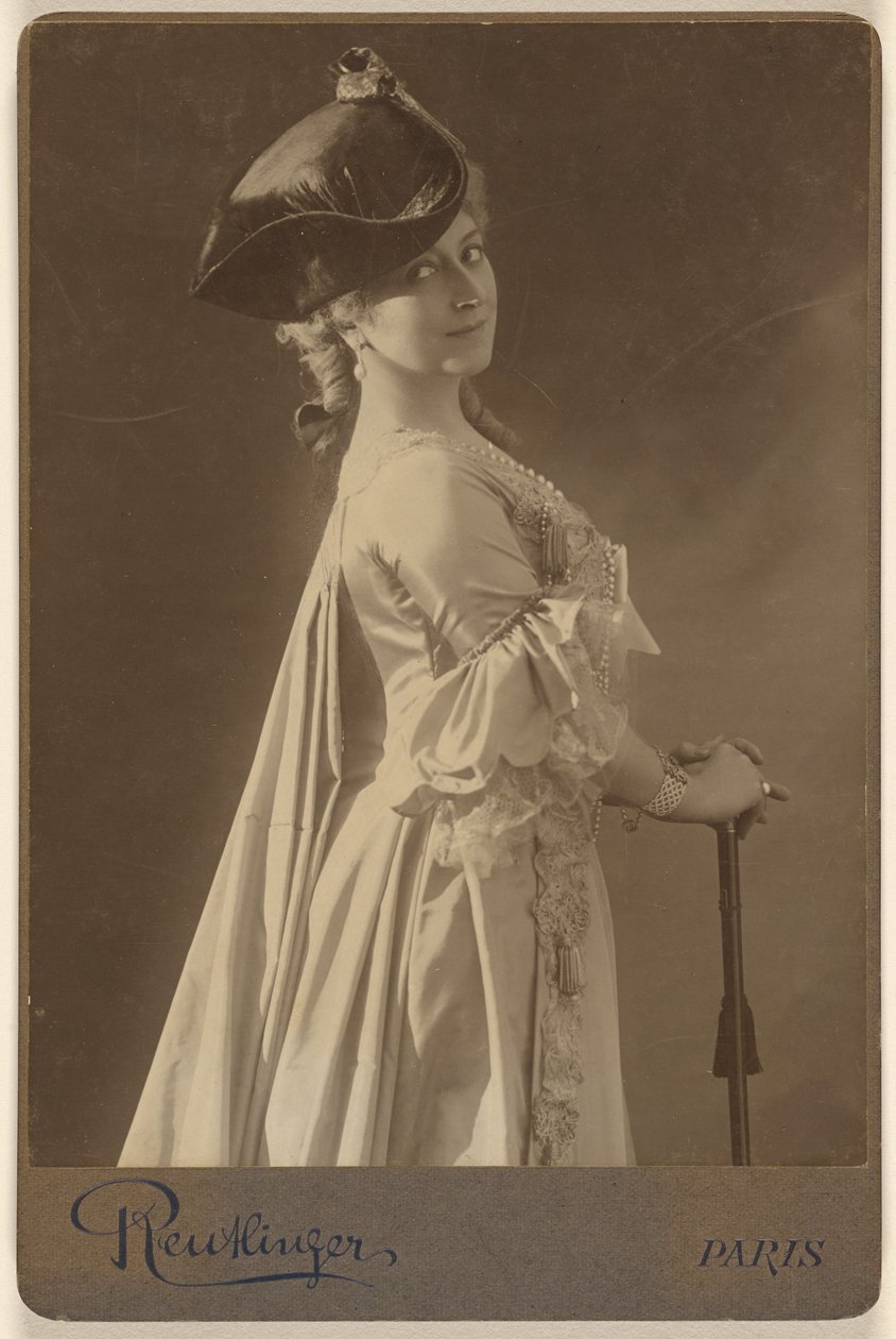 [Donna non identificata che indossa un cappello scuro, in piedi, con le mani appoggiate su un bastone da passeggio]. da Emile Auguste Reutlinger