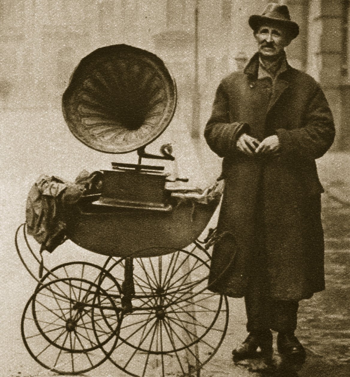 Un venditore ambulante intrattiene con un grammofono, trasportato in una carrozzina da English Photographer