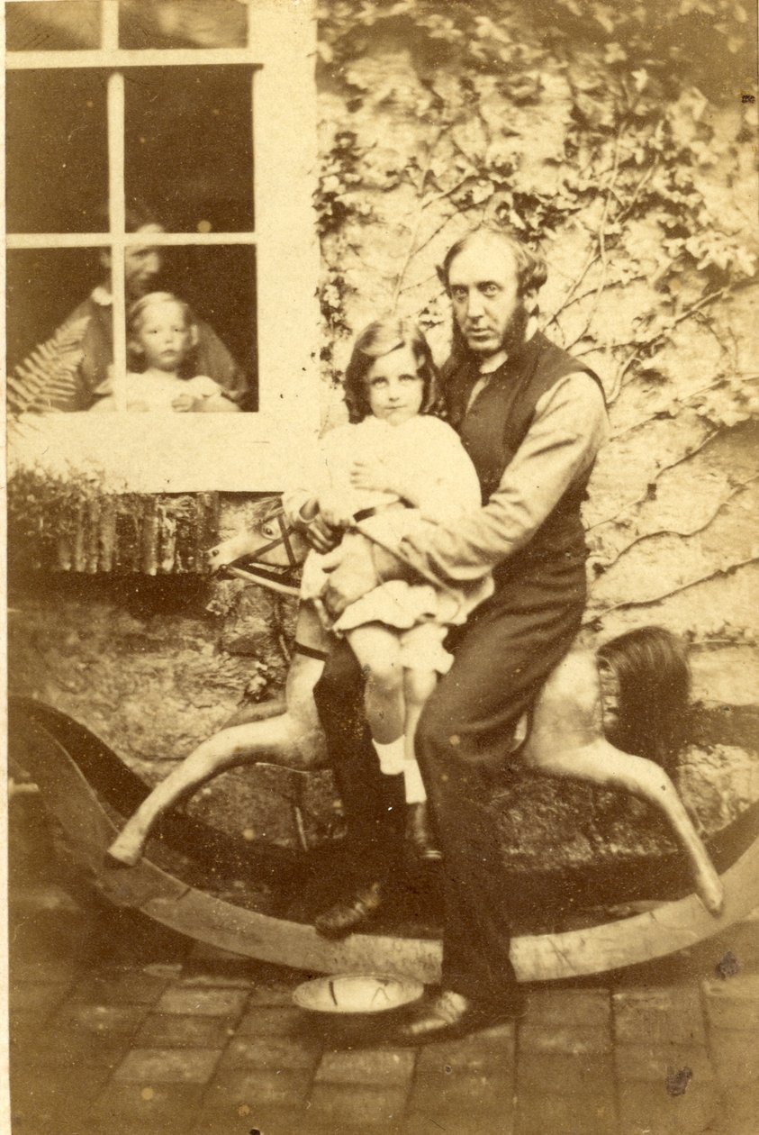 Padre e figlia seduti su un cavallo a dondolo con fratello e madre che guardano dalla finestra, 1860s da English Photographer