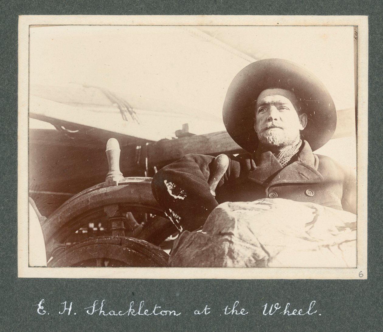 E H Shackleton in piedi accanto al timone della 