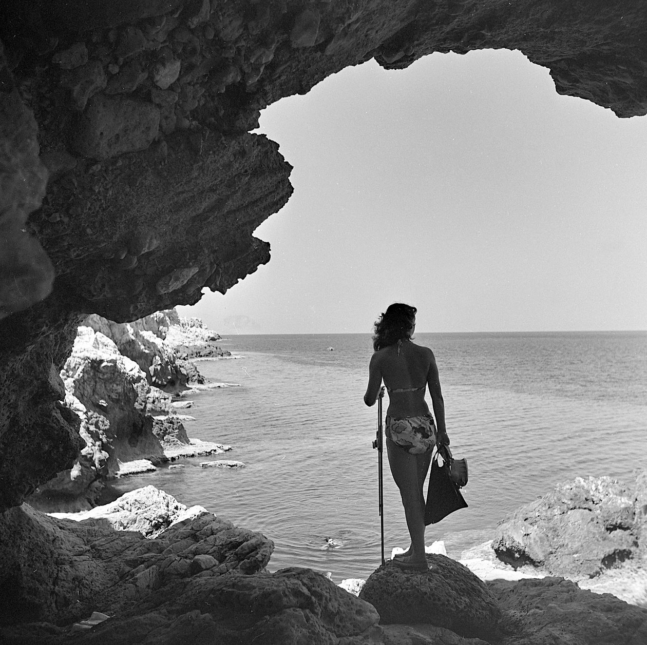 Bagnante sulla scogliera che guarda il mare presso il villaggio di Aspra, vicino a Palermo, Sicilia, 1950 circa (foto b/n) da Fosco Maraini