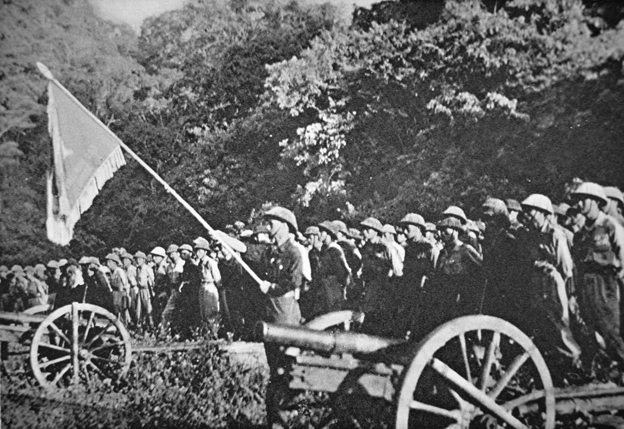 Truppe comuniste Viet Minh in parata con artiglieria leggera da campo, durante l