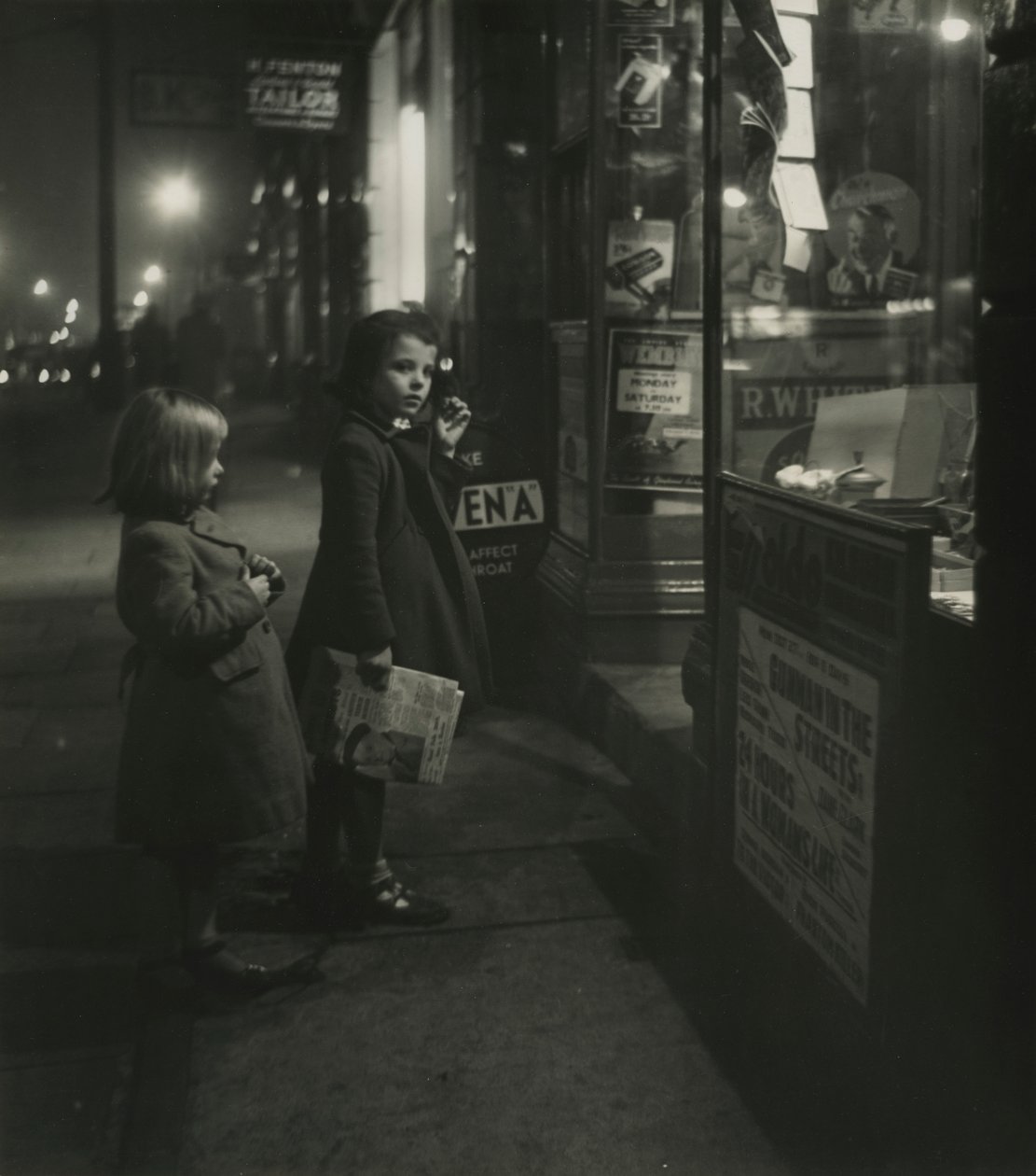 Due bambine con cappotti invernali fuori da un negozio di notte da Godfrey Macdominic
