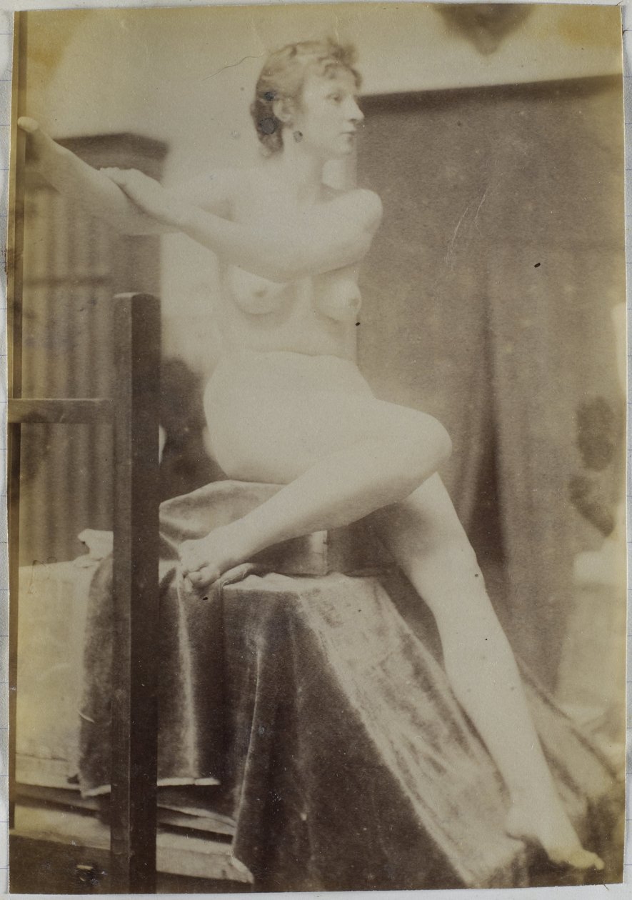 Studio di un modello femminile nudo, seduto su un podio accanto a un cavalletto e visto di fronte, nell