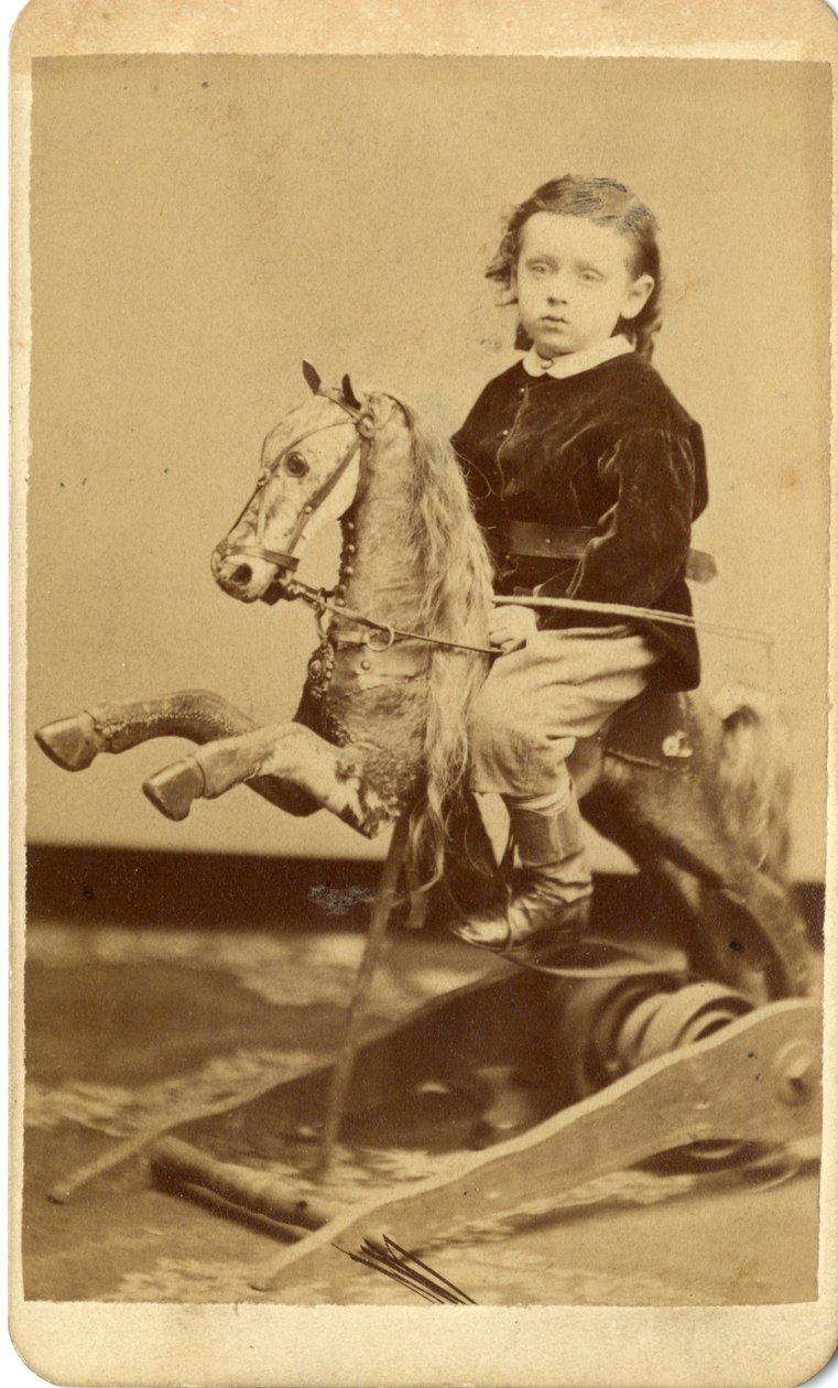 Ragazzino con frusta su cavallo a dondolo da John McCaffrey