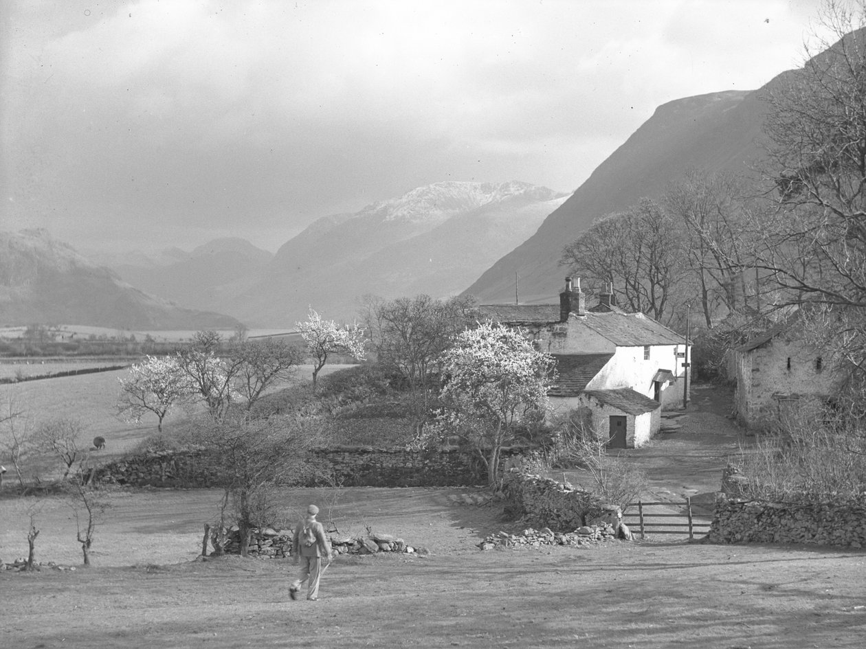 Un uomo che cammina verso un vicolo e la Gillerthwaite House, con il lago e le colline sullo sfondo da Joseph Hardman