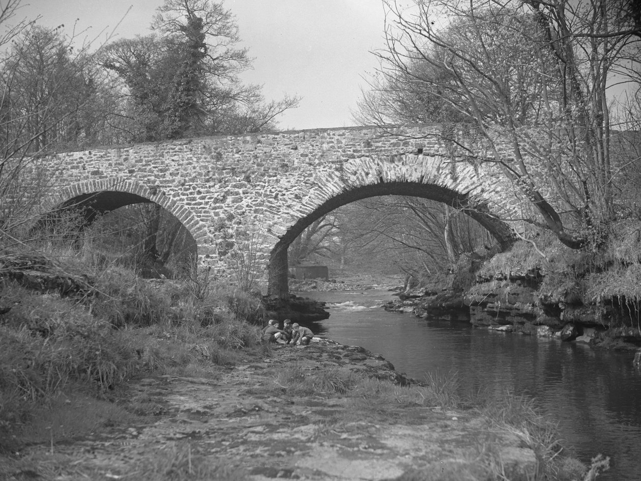 Gruppo di ragazzi accovacciati sulla riva del fiume sotto un ponte di pietra da Joseph Hardman