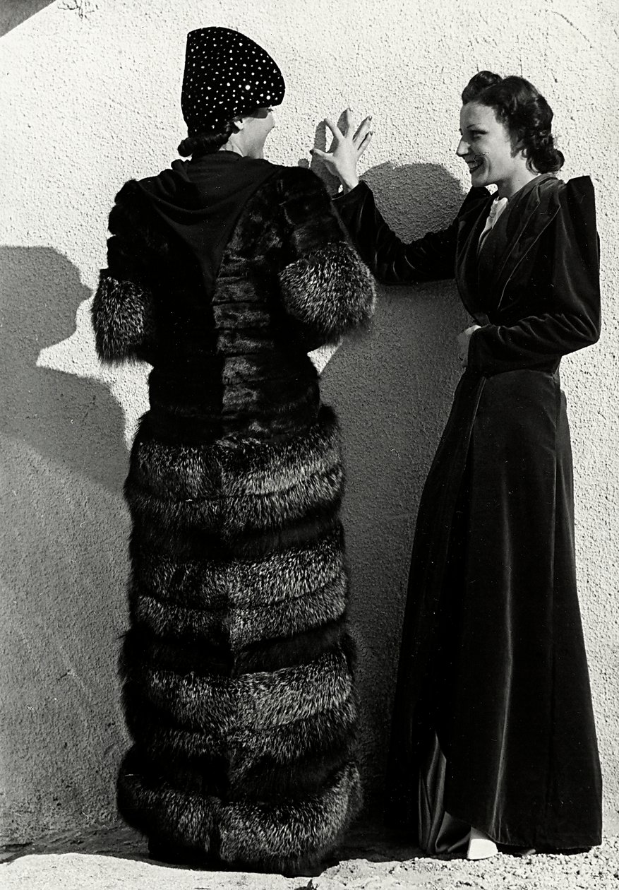 Due modelle presentano creazioni della casa di moda italiana "Dragoni". Una modella vista di spalle indossa un cappotto di volpe argentata. L