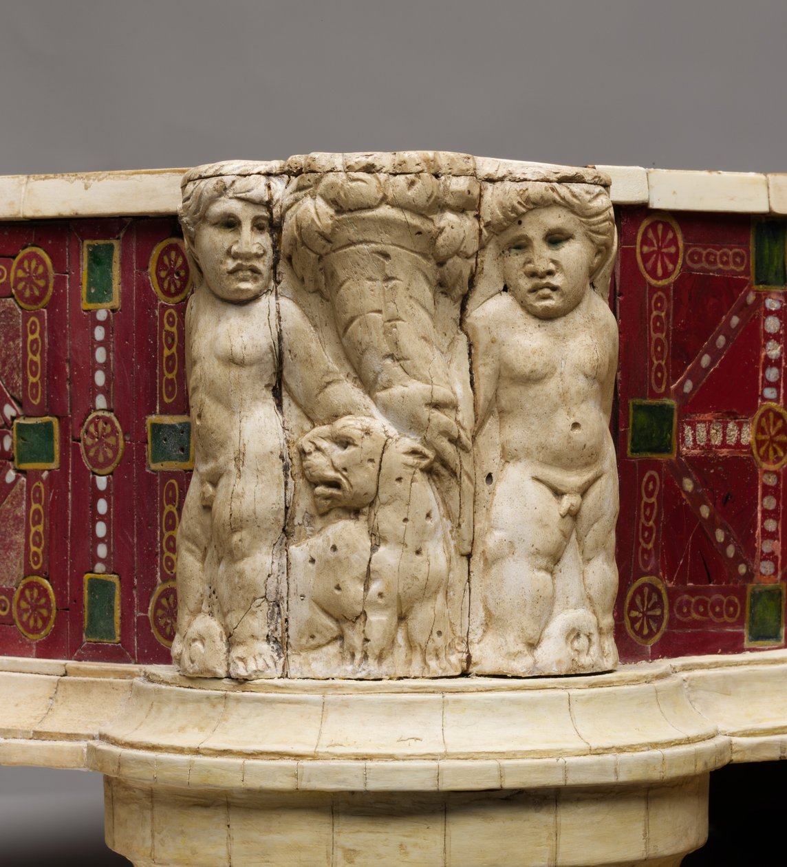 Dettaglio del poggiapiedi con intaglio osseo di cupidi, leopardi e cornucopie da Roman