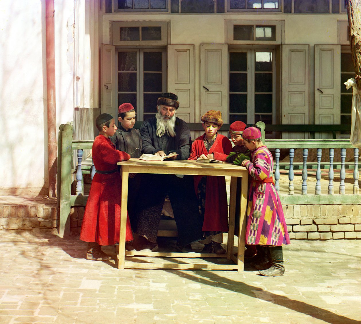 Un gruppo di bambini ebrei con un insegnante su un tavolo davanti a una casa, Samarcanda, Impero Russo, tra il 1905 e il 1915 da Sergey Prokudin Gorsky