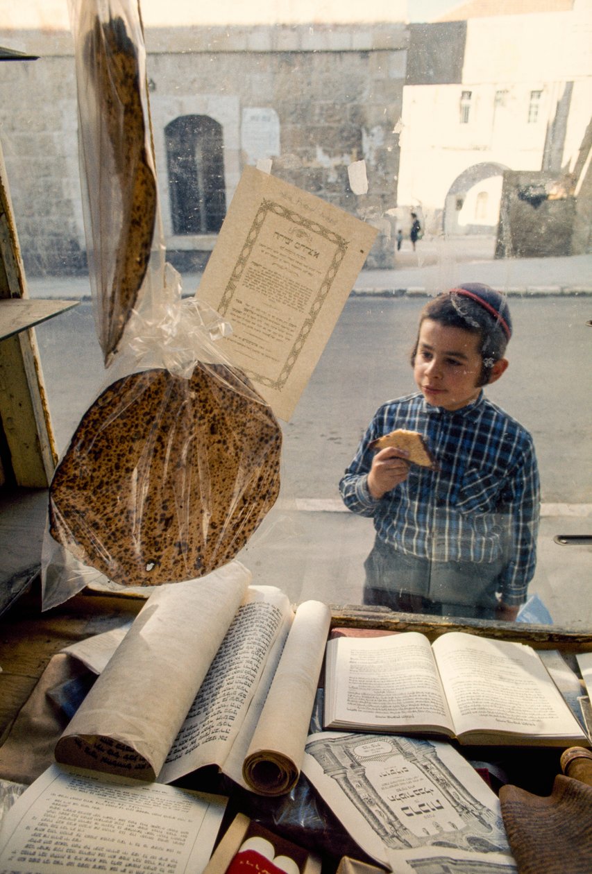 Ragazzo ebreo conservatore che mangia una torta guarda in una libreria religiosa da Ted Spiegel
