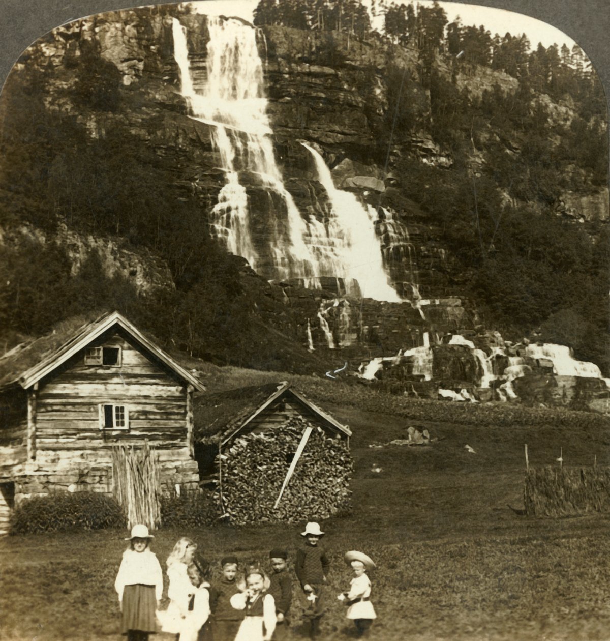 Bambini che giocano in un campo di un contadino con la cascata terrazzata di Tvinde, Vossevangen, Norvegia, c1905 da Unbekannt