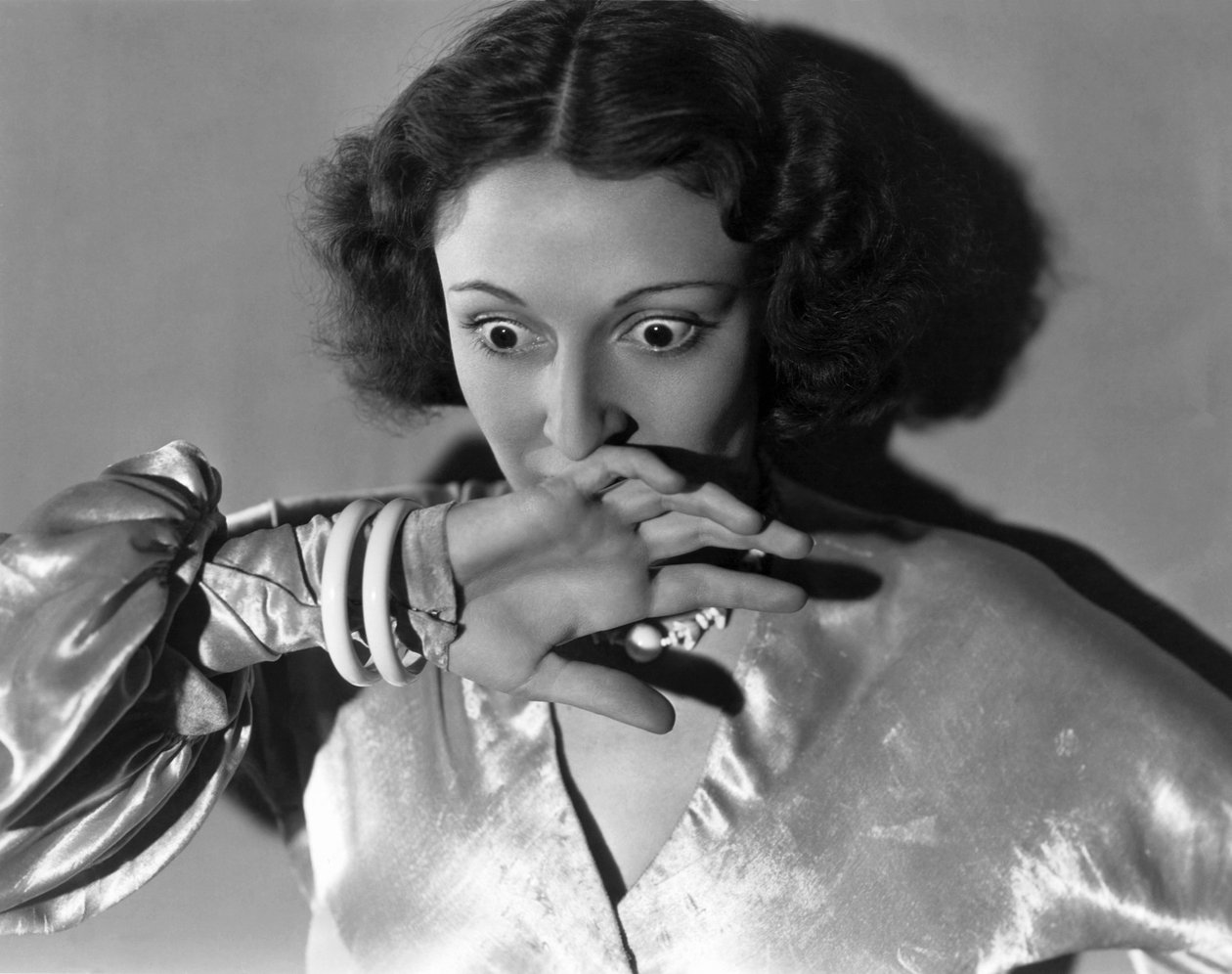 Hollywood, California: c.1932 Primo piano di una giovane donna che si copre la bocca per la paura. (foto b/n) da Unbekannt