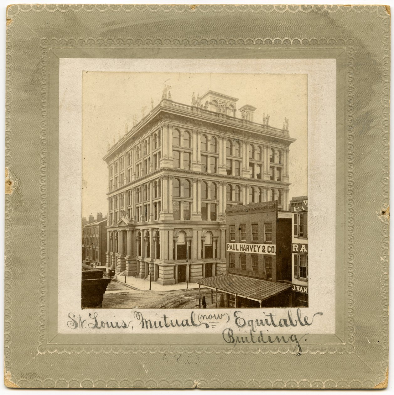 Fotografia di un edificio di sei piani con figure lungo la sommità. Sono visibili altri edifici ai lati. Edificio chiamato anche St. Louis Life Insurance Building da Unknown
