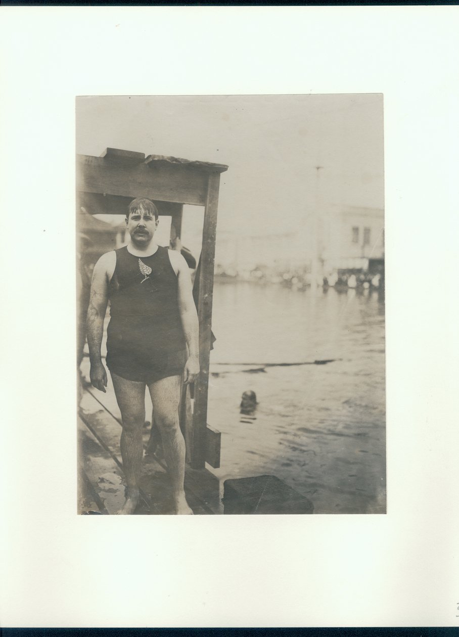 Uomo bagnato in costume da bagno su un molo di legno accanto a un piccolo lago con un uomo che nuota da Unknown