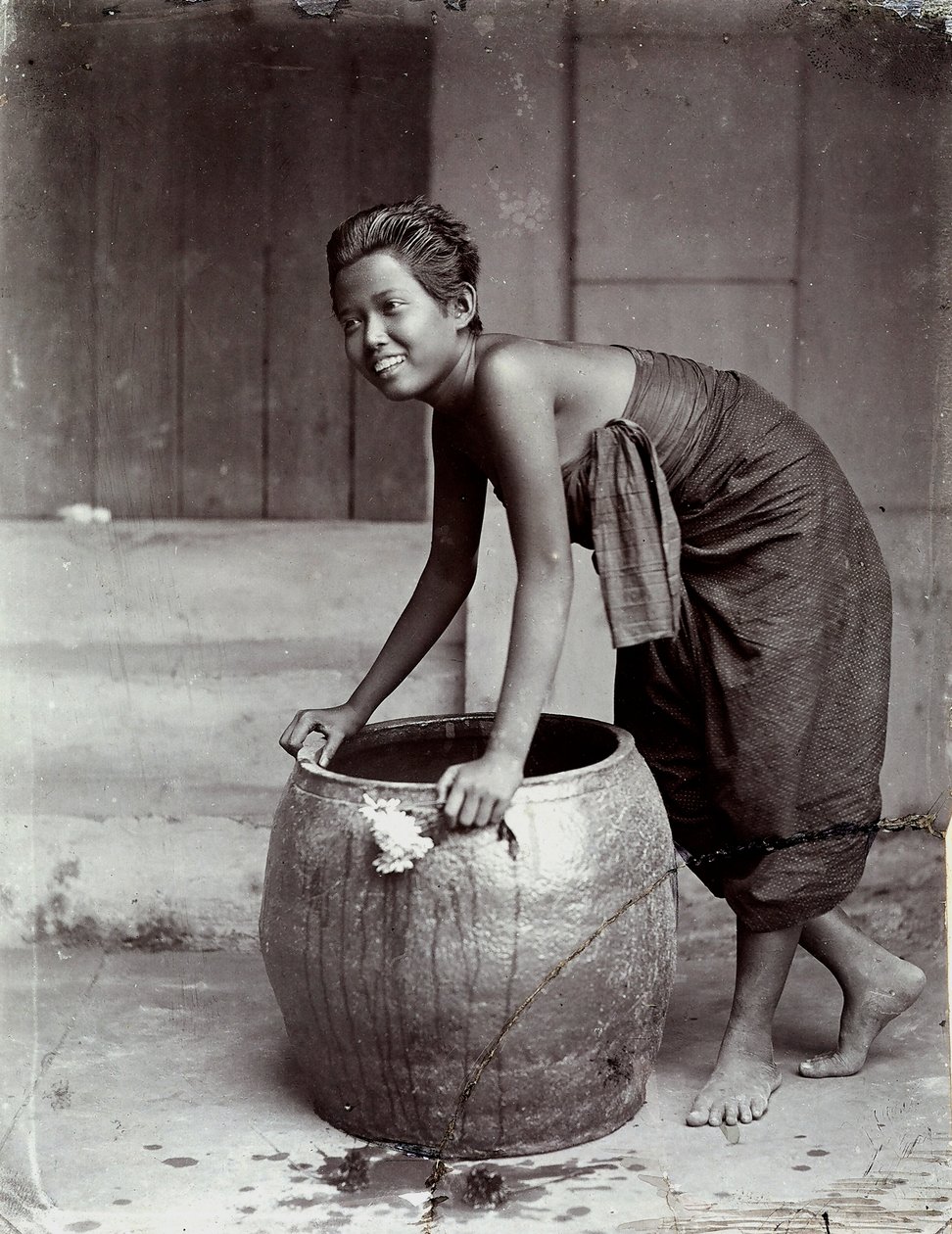 Giovane donna thailandese sorridente, spingendo un grande contenitore da Unknown photographer