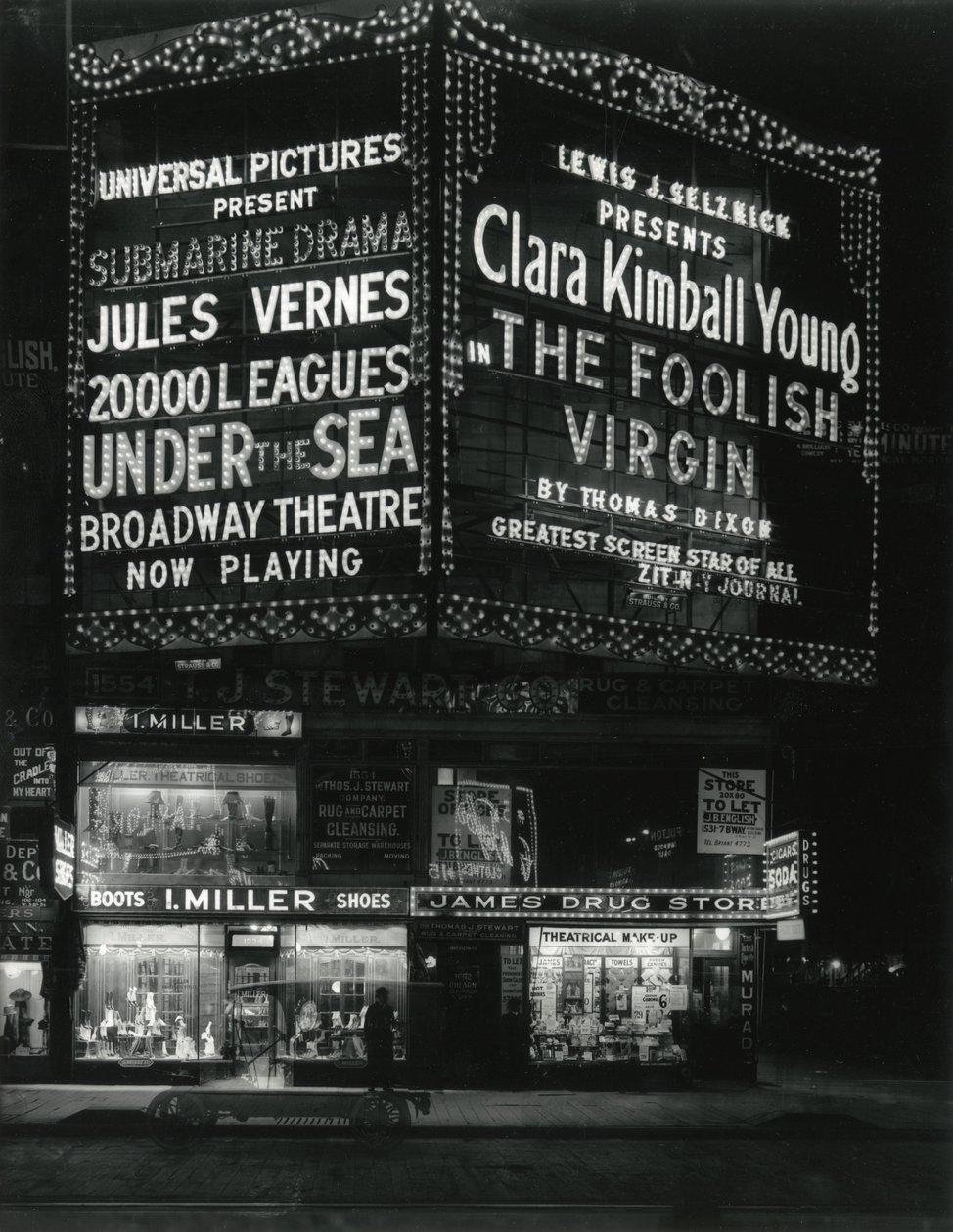 1554 Broadway alla 46th Street, I. Miller Shoes; James Drug Store, e grandi insegne per film illuminate sopra. da William Davis Hassler