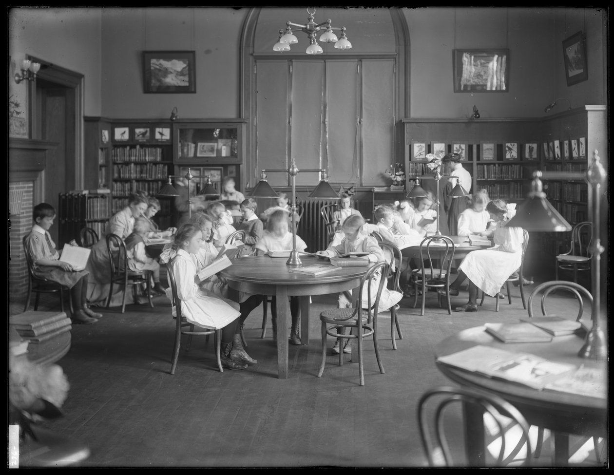 Bambini che leggono nella sala di lettura di una filiale non identificata della Biblioteca Pubblica del Queens Borough, c.1910 da William Davis Hassler