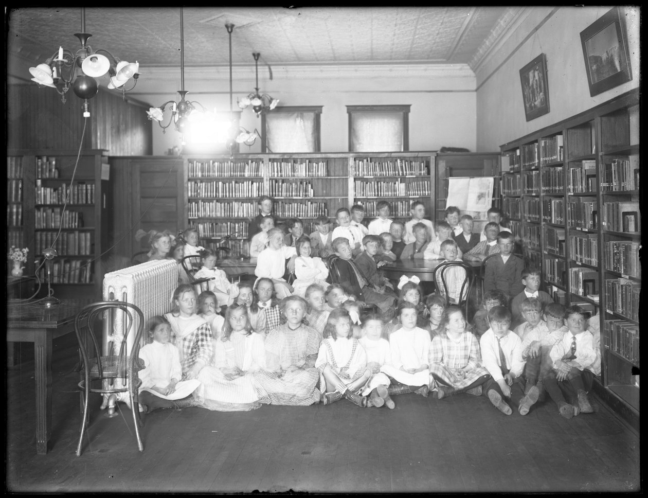 Ritratto di gruppo di bambini nella sala di lettura di una filiale non identificata della Queens Borough Public Library, c.1910 da William Davis Hassler