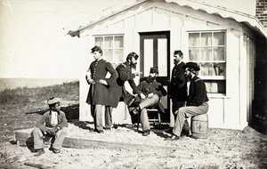 Cinque soldati della Guerra Civile riuniti su un portico di terra fuori casa, giovane afroamericano seduto vicino a loro, 1861-65 da American Photographer