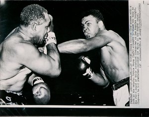 Il Giovane Cassius Clay colpisce con un sinistro il veterano Archie Moore nel primo round del combattimento a Los Angeles da American Photographer