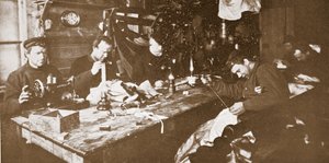 Nella capanna durante il pieno inverno, gli uomini impegnati a cucire pellicce per abiti da usare nelle slitte primaverili, pub. Londra 1907 (foto b/n) da Anthony Fiala