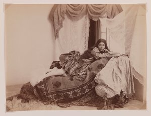 Foto in studio di una donna reclinata che legge un libro da Antoin Sevruguin