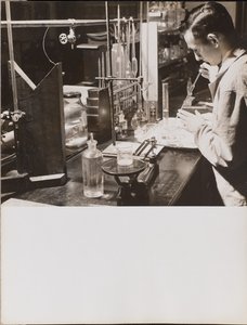 [Uomo in laboratorio usa entrambe le mani per mettere una grande pipetta in un becher]. da Arnold Eagle