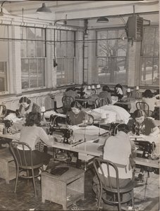 [Donne sedute alle scrivanie lavorano alle macchine da cucire] da Arnold Eagle