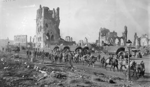Una sezione di mitragliatrici australiana non identificata con cavalli da soma che passa le rovine della Cloth Hall. Nota diversi camion a motore parcheggiati sullo sfondo, 19 ottobre 1917 da Australian Photographer