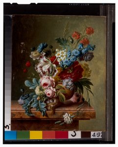 Un vaso di fiori su un bordo di marmo e un cesto di fiori con un cardellino