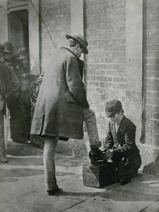 Un giovane lustrascarpe che lucida le scarpe di un uomo per strada da English Photographer