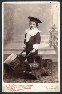 Ragazzo con un trenino giocattolo e una carriola da English Photographer
